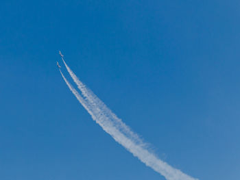 Low angle view of airshow against clear blue sky