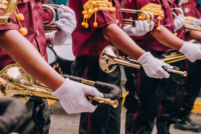 Midsection of men holding musical instrument on road