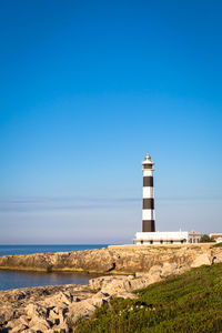 Lighthouse by sea against sky