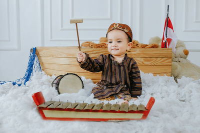 
a baby boy wearing javanese traditional clothes while playing javanese musical instruments