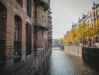 Canal amidst buildings in city against sky