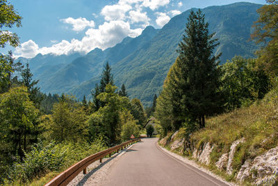 Road amidst trees and mountains against sky