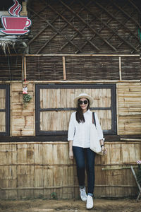 Portrait of woman in sunglasses standing against barn