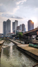 River amidst buildings in city against sky