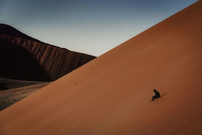 Full length of man sitting on desert