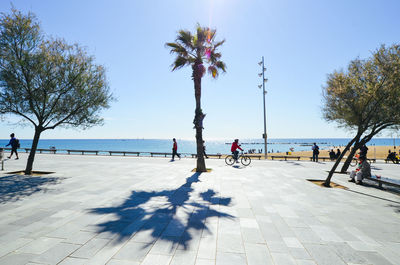 People at promenade against sky on sunny day