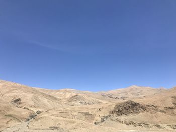 Scenic view of arid landscape against clear blue sky