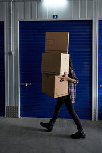 Beautiful brunette woman carrying cardboard boxes in a self storage after making a move