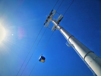 Low angle view of telephone pole against clear blue sky