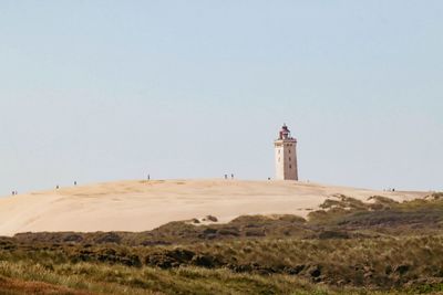 Lighthouse by sea against clear sky