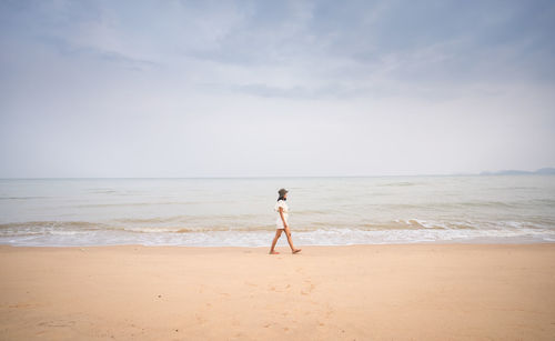 Asian female tourists for a walk relaxes on the beach.