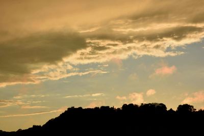 Low angle view of silhouette trees against dramatic sky