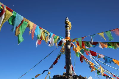 Low angle view of flags hanging against blue sky