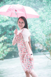 Young woman with umbrella standing in rain