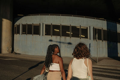 Rear view of multiracial teenage girls walking crossing street in city