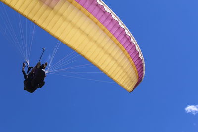 Low angle view of person paragliding against clear blue sky