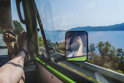 Low section of man in car against sky