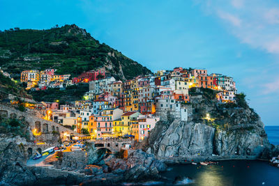 Buildings on mountain by sea at manarola during dusk