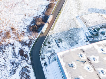 Aerial follow shot of white semi truck with cargo trailer attached moving through industrial  