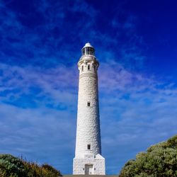 Low angle view of lighthouse by building against sky