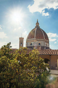 Roof in building, tree and cathedral dome with sunny blue sky in the city of florence, italy.