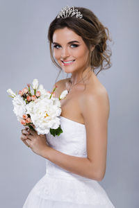 Side view of bride holding bouquet against gray background