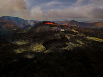 Scenic view of erupting lava against sky during sunset