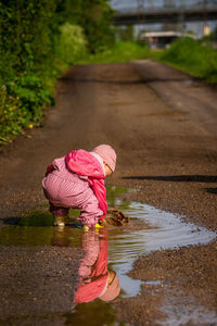 A small child is playing in a rain puddle