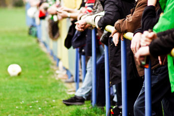 Spectators standing by railing on playing field