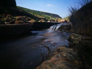 River flowing amidst rocks against clear sky