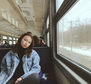 Portrait of woman sitting by window in train 