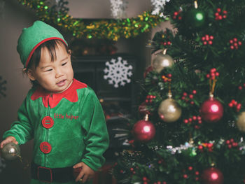 Cute baby girl by christmas tree at home