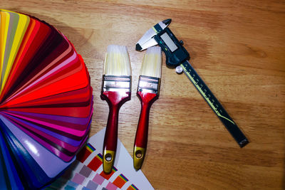 High angle view of paintbrushes by color swatches on table