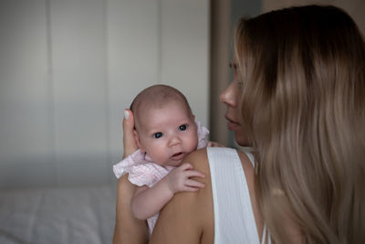 Close-up of mother carrying newborn daughter at home