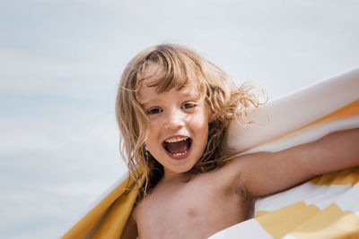 Girl laughing whilst wrapped in a striped towel at the beach