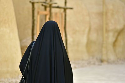 Rear view of woman wearing burka against built structure