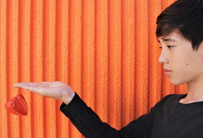 Close-up portrait of boy looking away against orange wall