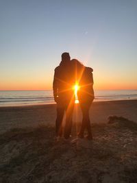 Silhouette man standing on beach against sky during sunset