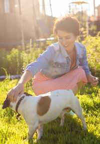 Portrait of young woman with dog on field