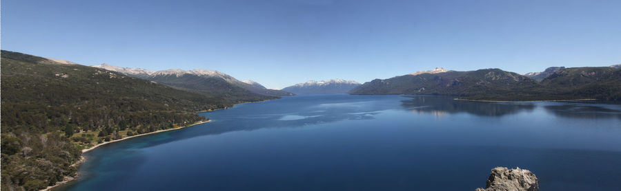 Scenic view of lake and mountains against clear blue sky