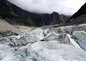 Scenic view of river flowing through mountains against sky