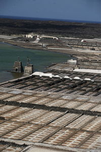 High angle view of salt flats by sea against blue sky