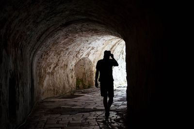 Rear view of silhouette man walking in tunnel