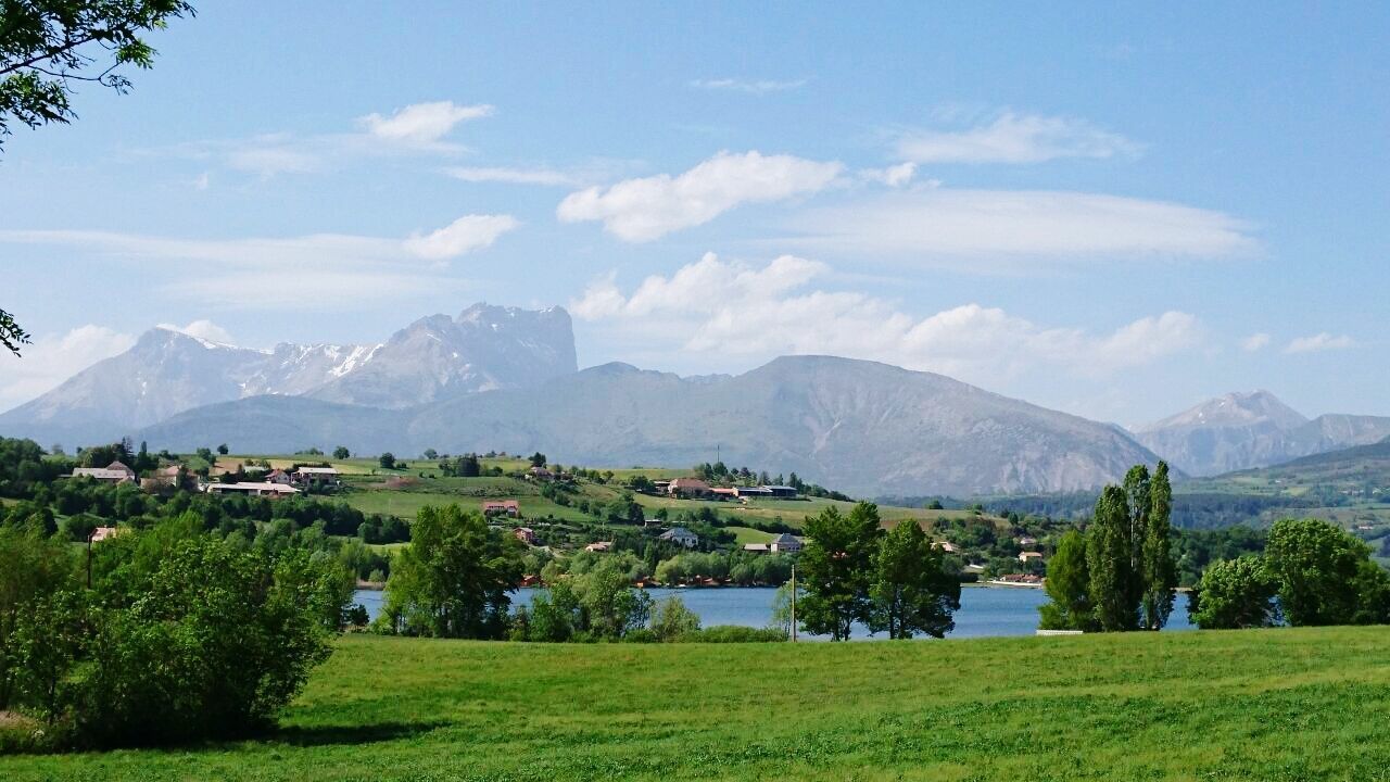 mountain, mountain range, sky, tranquil scene, landscape, scenics, tranquility, beauty in nature, grass, tree, green color, nature, cloud, cloud - sky, built structure, idyllic, non-urban scene, building exterior, field, architecture