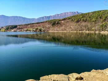 Scenic view of lake and mountains against clear blue sky