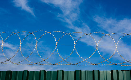 Low angle view of chainlink fence against blue sky