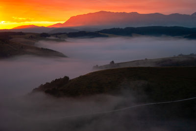 Scenic view of silhouette mountains against orange sky