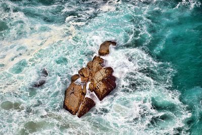 High angle view of wave splashing on rock