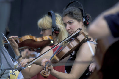 Young woman playing guitar at music concert