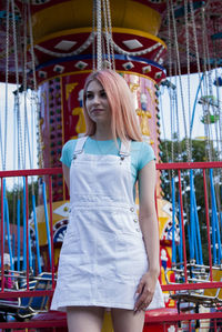 Young woman standing against carousel at amusement park